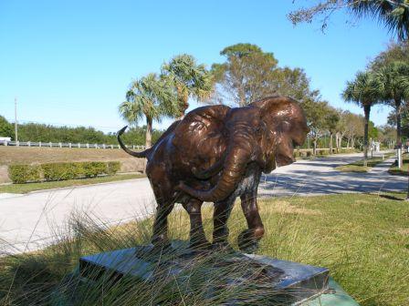 Bronze elephant statue in grass area near sidewalk